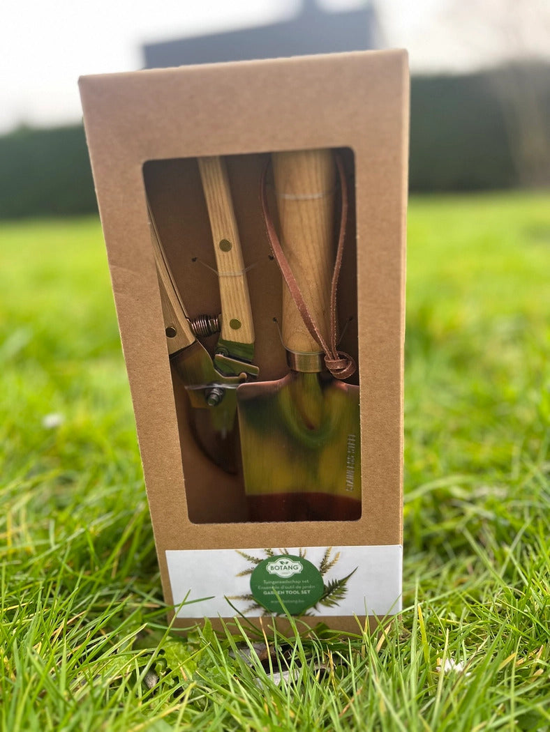 Lækkert sæt med haveskovl og grensaks i kobber. Sættet står på en grøn græsplæne