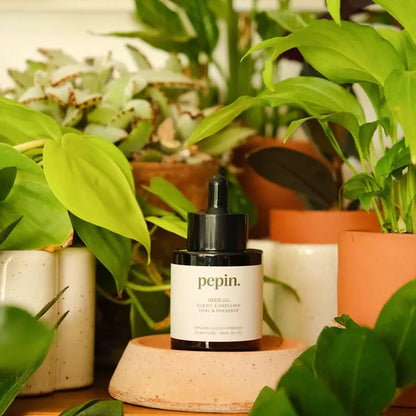 Lille flaske med neem olie, der står blandt en masse planter