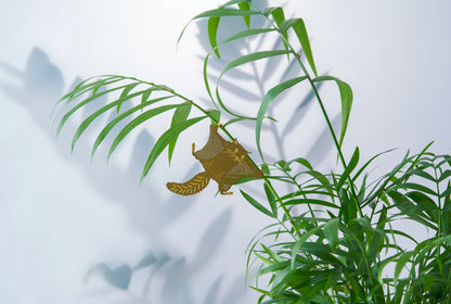 Lille flyveegern som messingfigur i en grøn plante